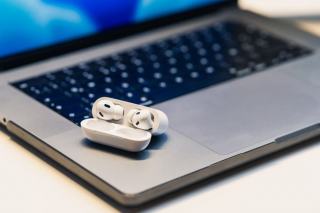 Un casque sans fil posé entre un ordinateur portable et un téléphone sur un bureau