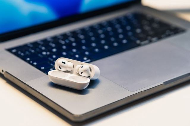 Un casque sans fil posé entre un ordinateur portable et un téléphone sur un bureau